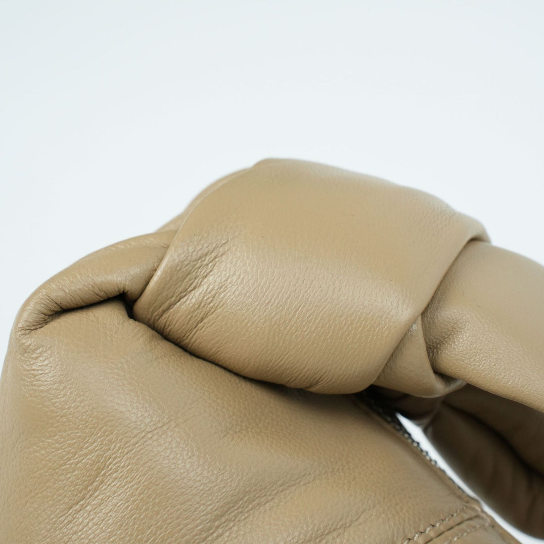 Logo-free lambskin croissant shoulder bag — tan knotted handle close-up