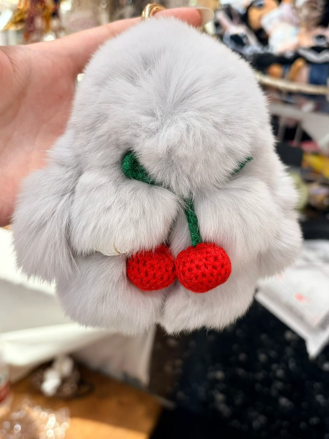 Light gray fluffy bunny bag charm with knitted red cherries close-up