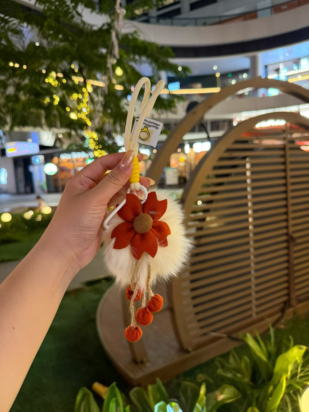 Ivory fluffy flower bag charm with rust orange petals and pom-pom tassels