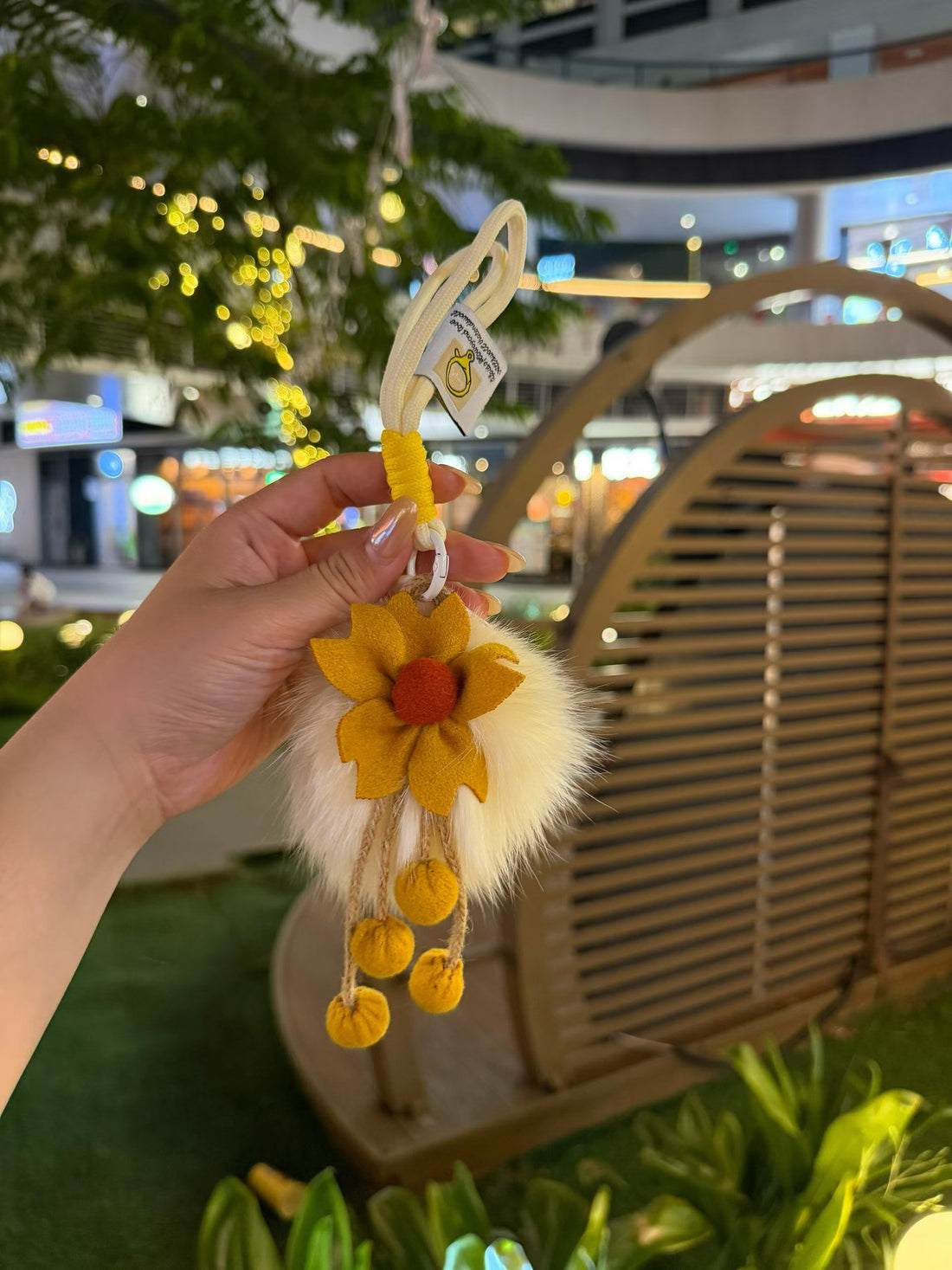 Ivory fluffy flower bag charm with mustard yellow petals and pom-pom tassels