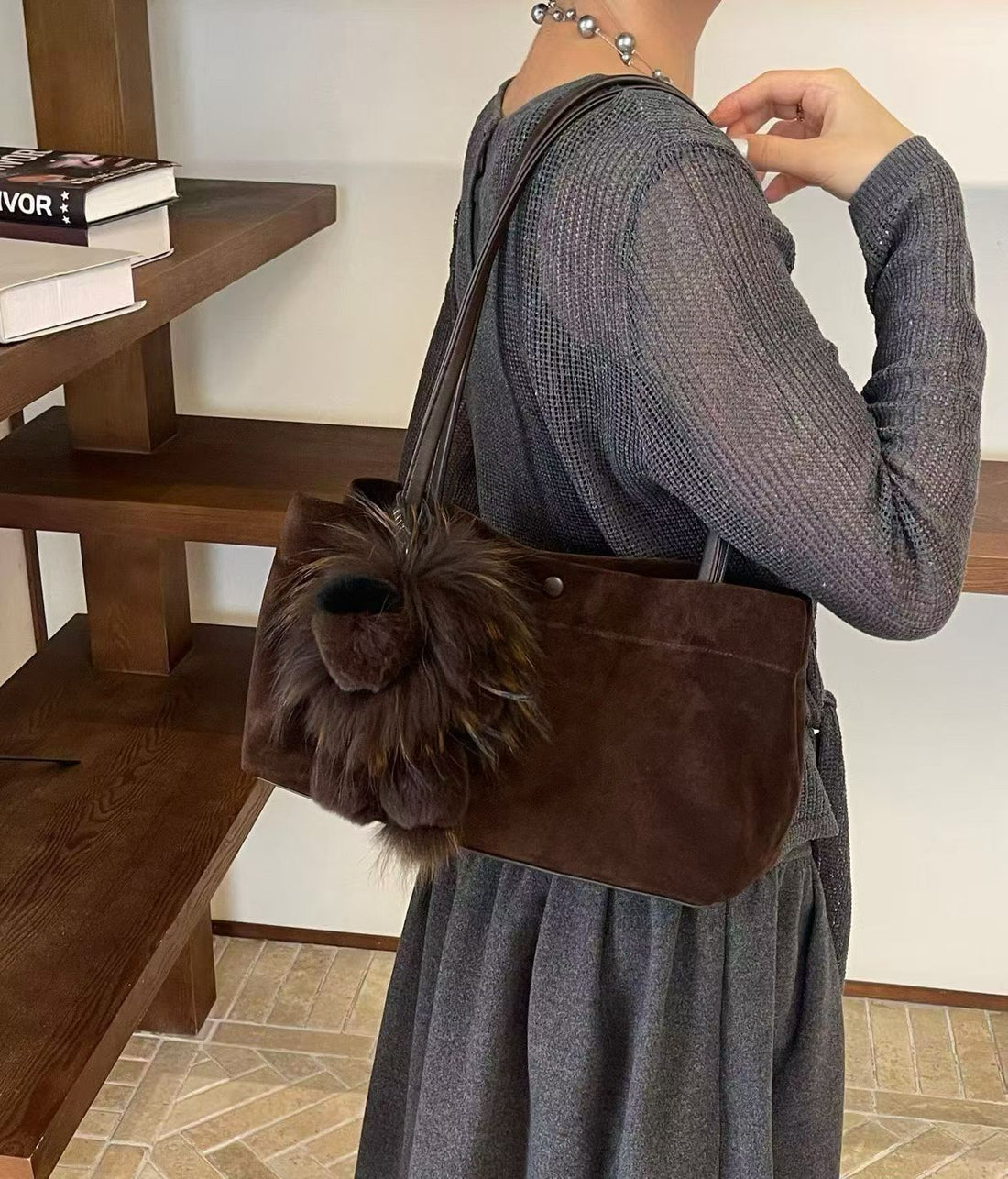 Chocolate brown fluffy lion bag charm attached to a brown suede tote