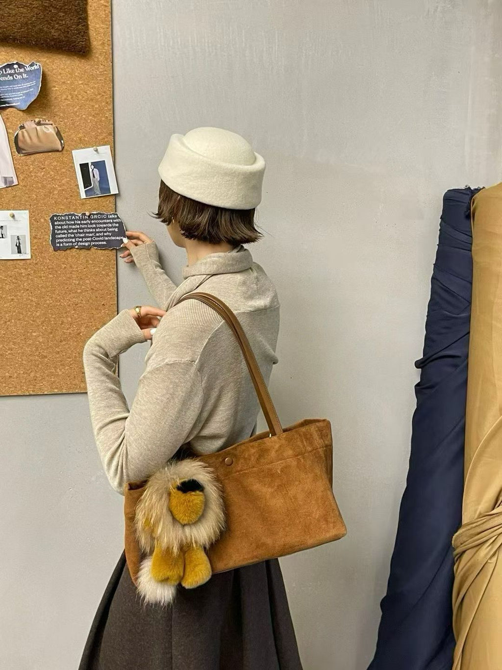 Golden ochre fluffy lion bag charm styled on a brown shoulder tote