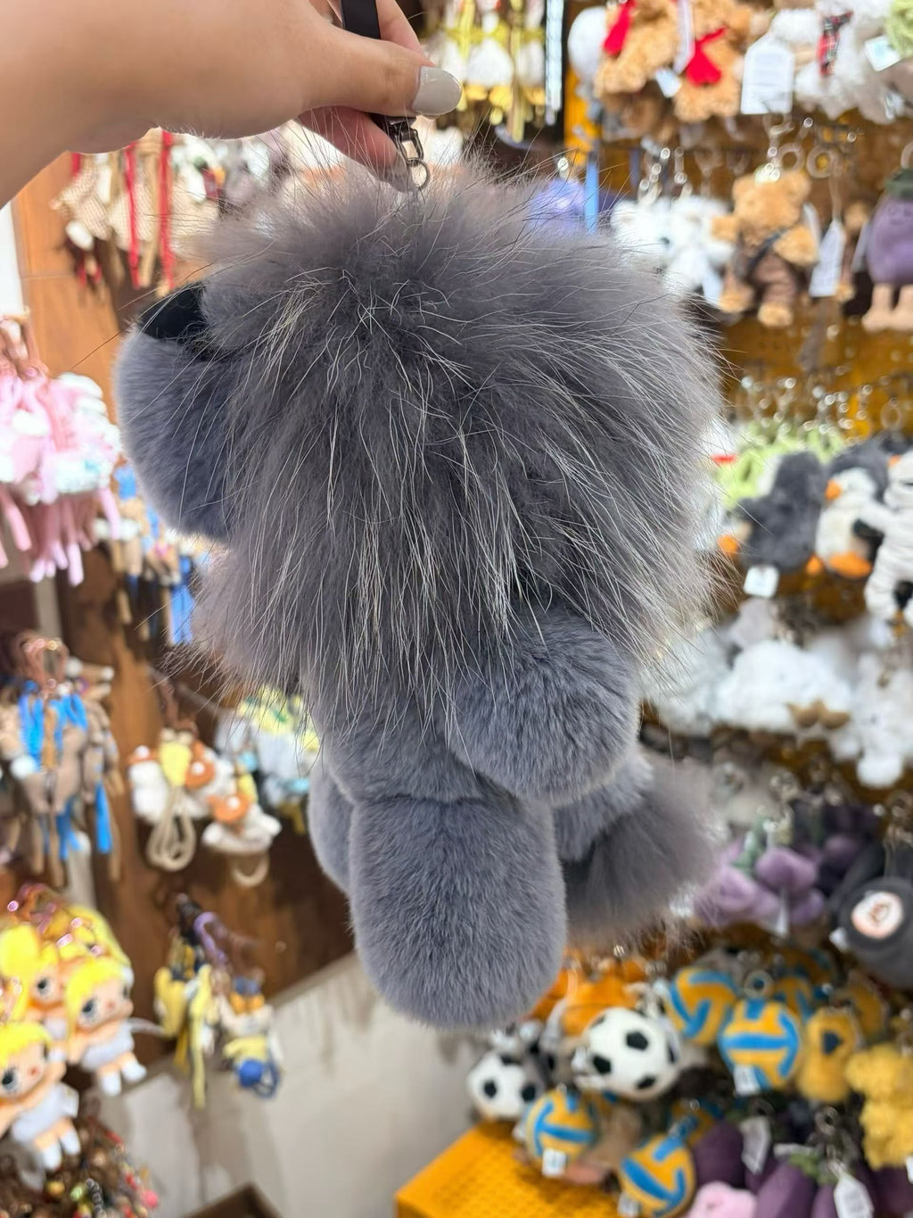 Back view of silver gray fluffy lion bag charm with long mane