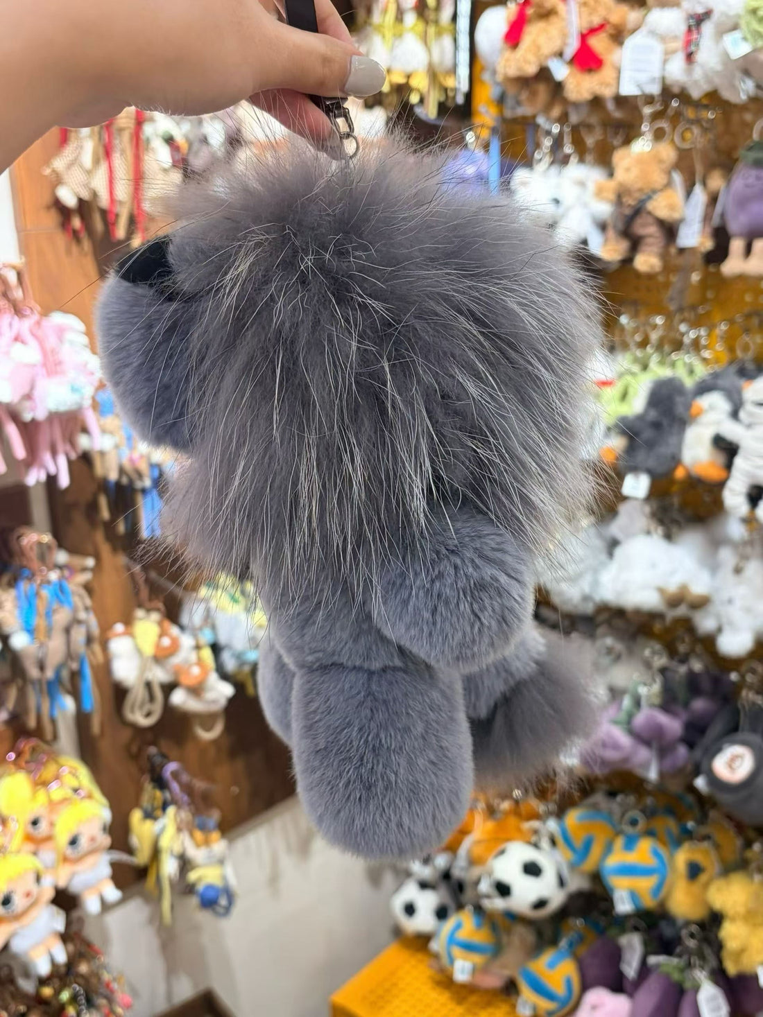 Back view of silver gray fluffy lion bag charm with long mane