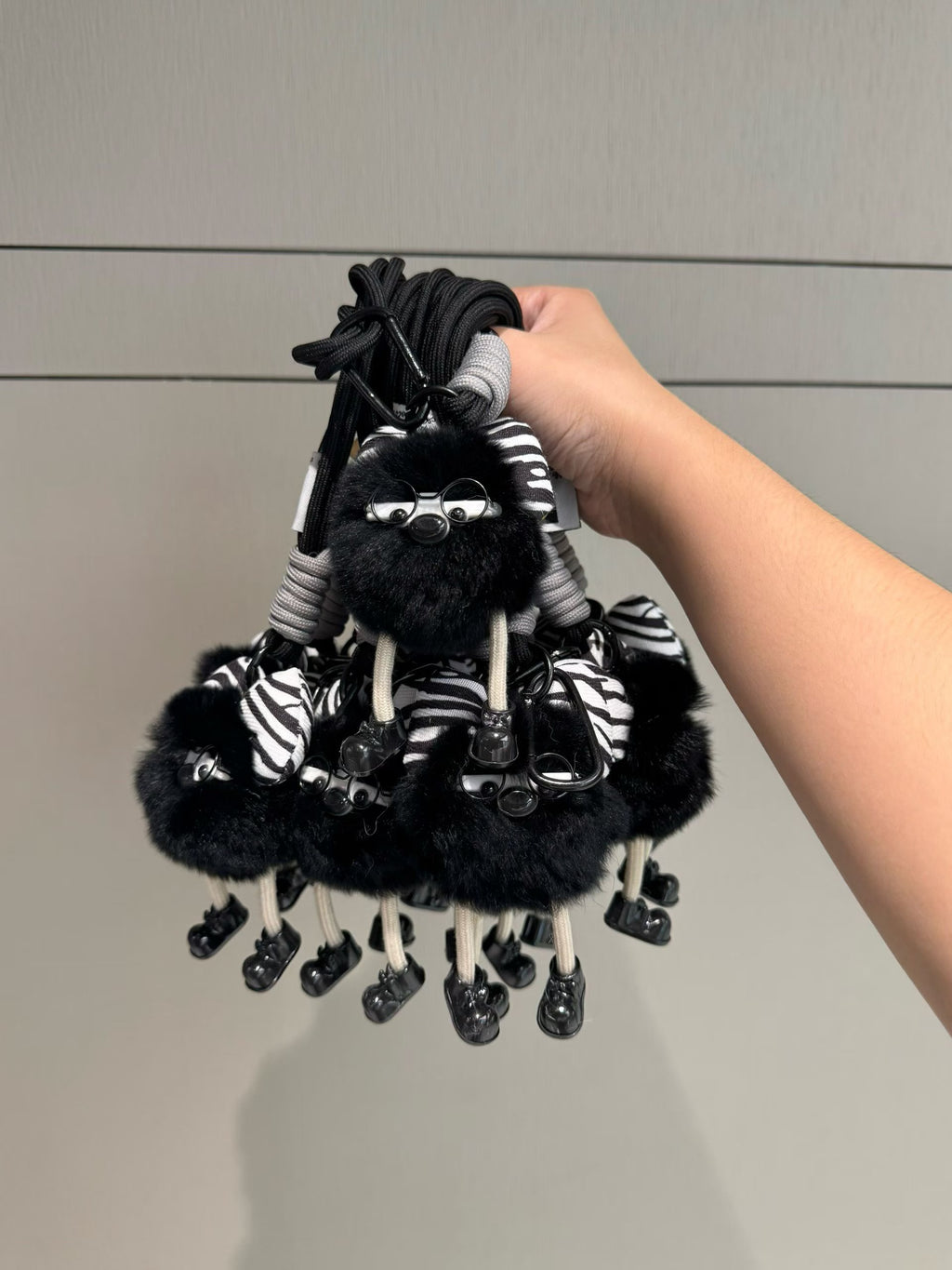 Black fluffy character bag charm with zebra bow glasses and dangling legs