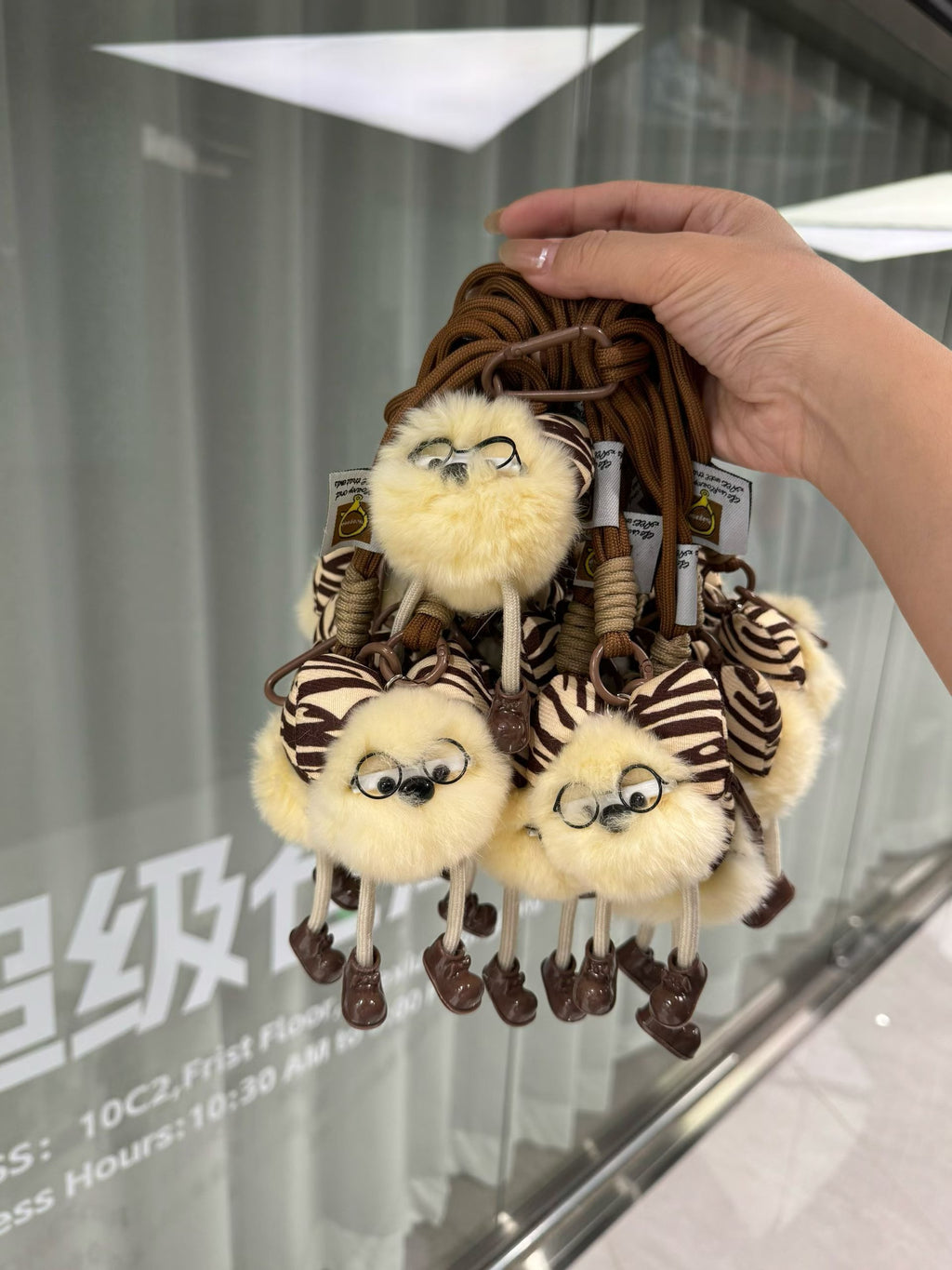 Cream fluffy character bag charm with zebra bow glasses and brown rope loop