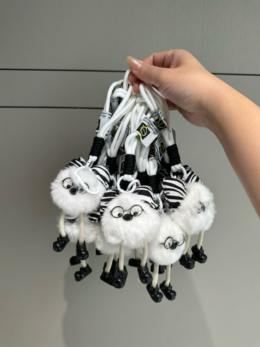 White fluffy character bag charm with zebra bow glasses and dangling legs