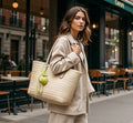 Woman styling a lime green apple bag charm on a woven tote